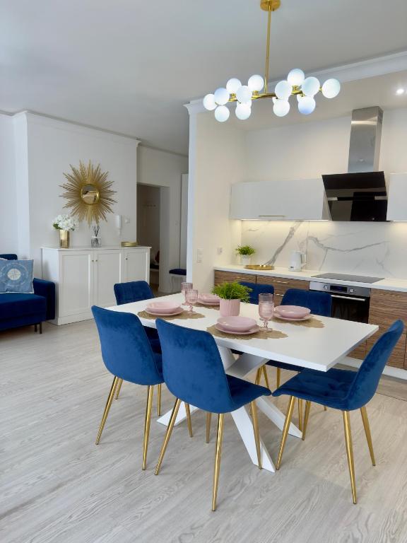 een keuken en eetkamer met een witte tafel en blauwe stoelen bij Apartament Portowy in Giżycko