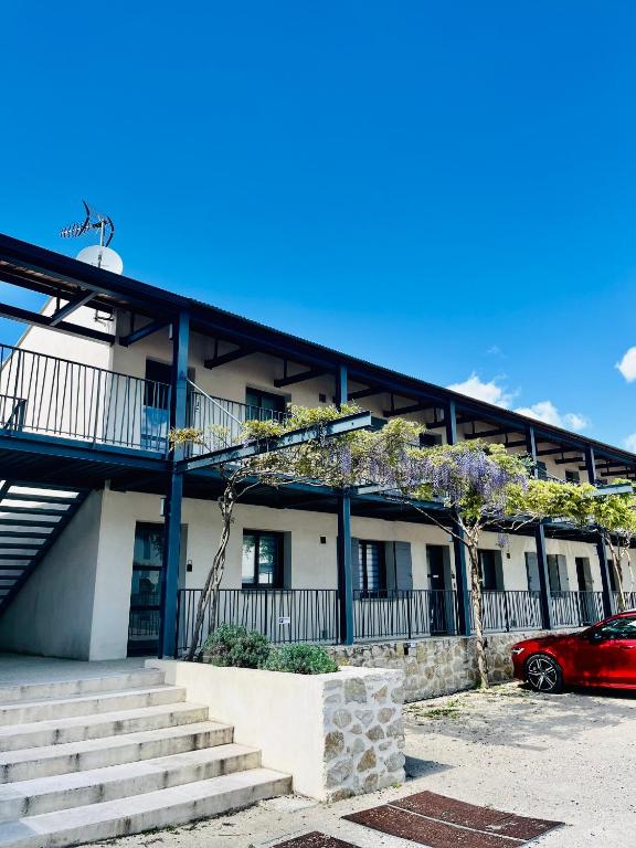 un bâtiment avec une voiture rouge garée devant lui dans l'établissement Loft du Cycliste, à Malaucène