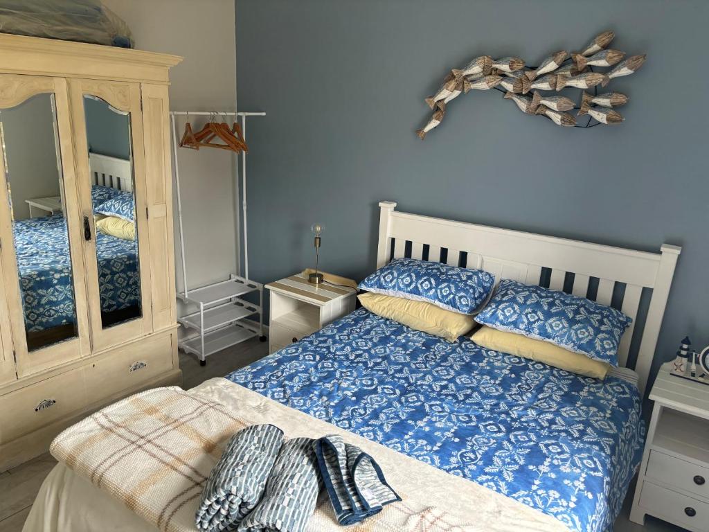 a blue bedroom with a bed and a mirror at Hoek Wyn en Sinker in Struisbaai