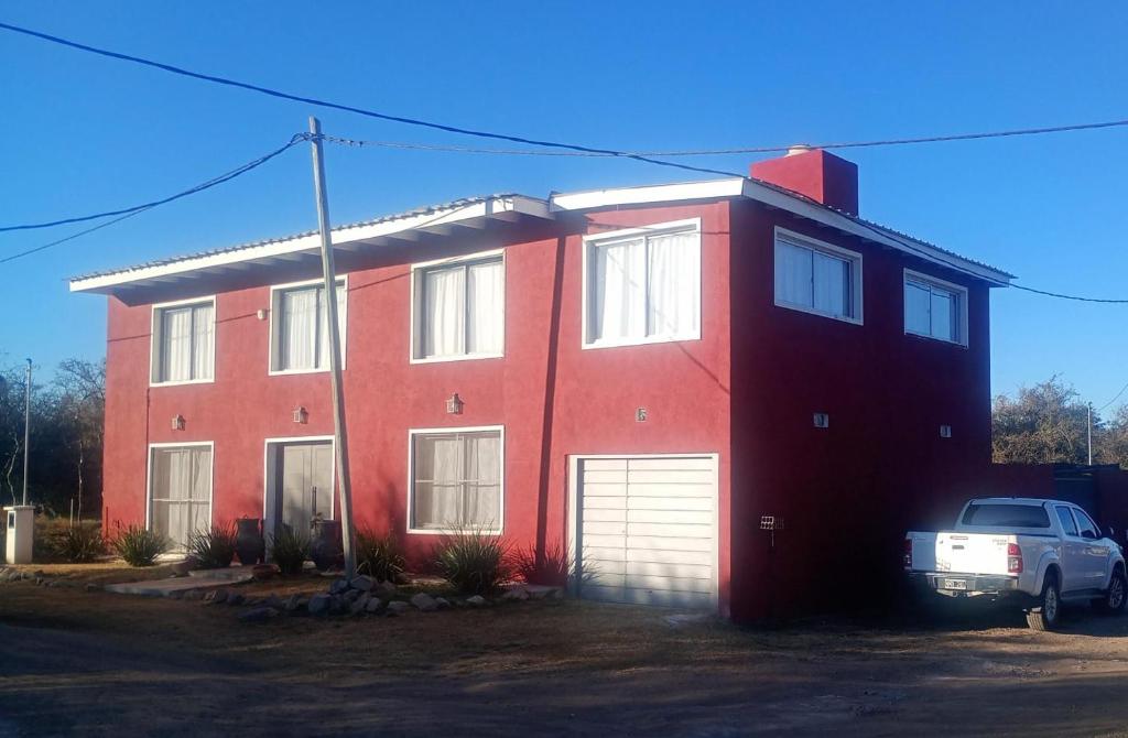una casa rossa con una macchina parcheggiata di fronte di Las Brisas - Hospedaje Serrano a Santa María