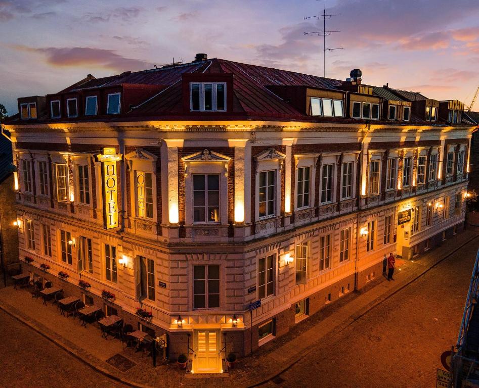 Narożny hotel oświetlony nocą, ciepłe światła elewacji i brukowana ulica, elegancka atmosfera.