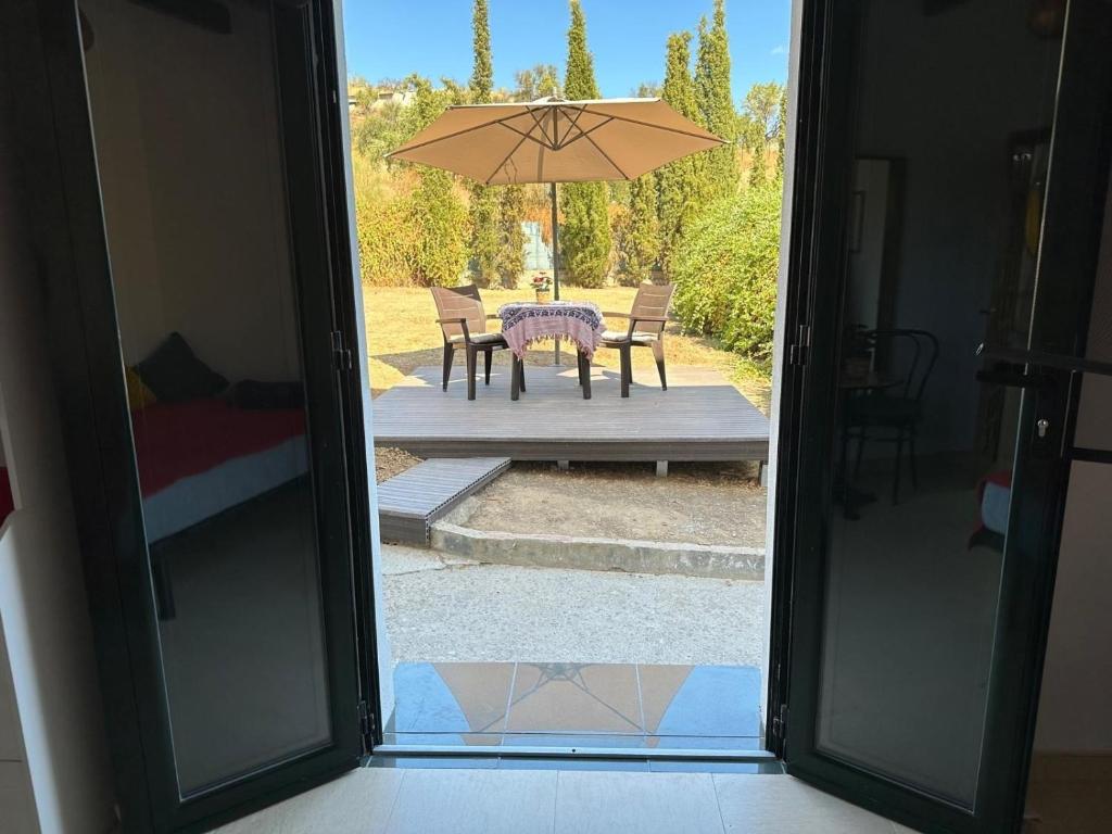 Una puerta abierta a un patio con una mesa y una sombrilla. en Habitacion Oliva, en Olvera