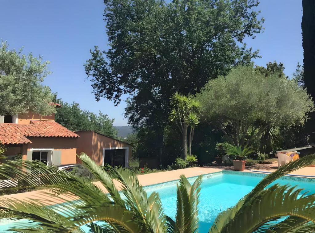 a swimming pool in front of a house with trees at Studio - les Adrets Esterel in Fréjus
