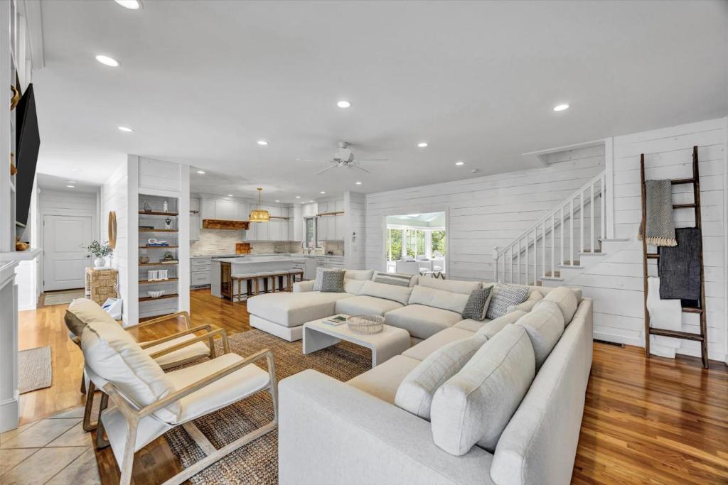 ein weißes Wohnzimmer mit einem weißen Sofa und Stühlen in der Unterkunft Spacious 7 Bed Retreat with Game Room, Deck, Yard, Half a Block from Ocean, Host Up to 22 Across 16 Beds, Gas Fireplace, Gas Grill, Ample Parking, Walk to Menauhant Beach, 24 Hr Hospitality in Falmouth