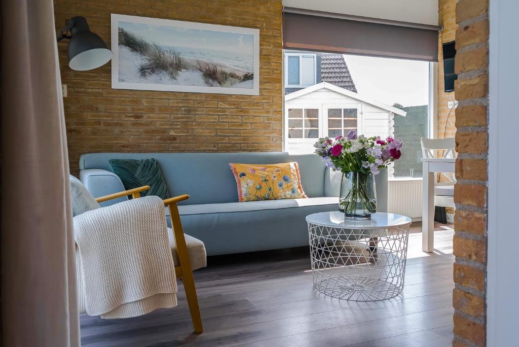 een woonkamer met een blauwe bank en een tafel bij -Casa Nova- nabij het meer, duinen en restaurants in Noordwijkerhout