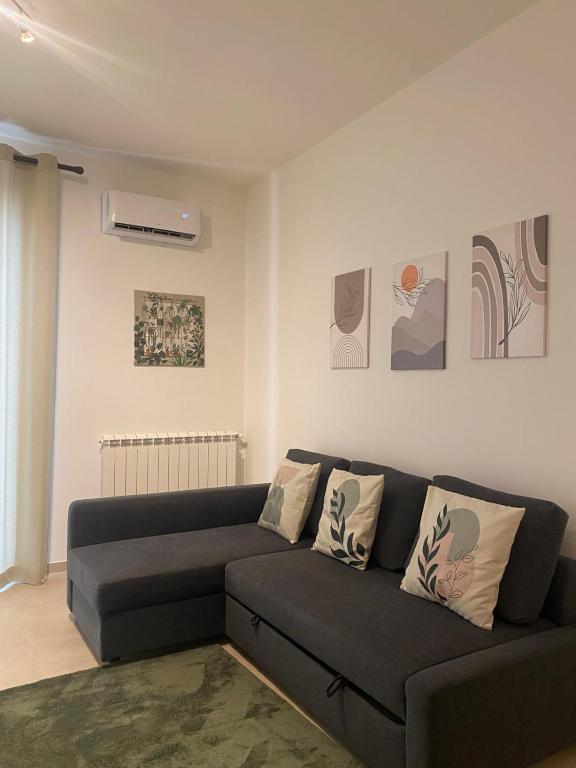 a living room with a black couch and some paintings at Ma Home in Cinisi