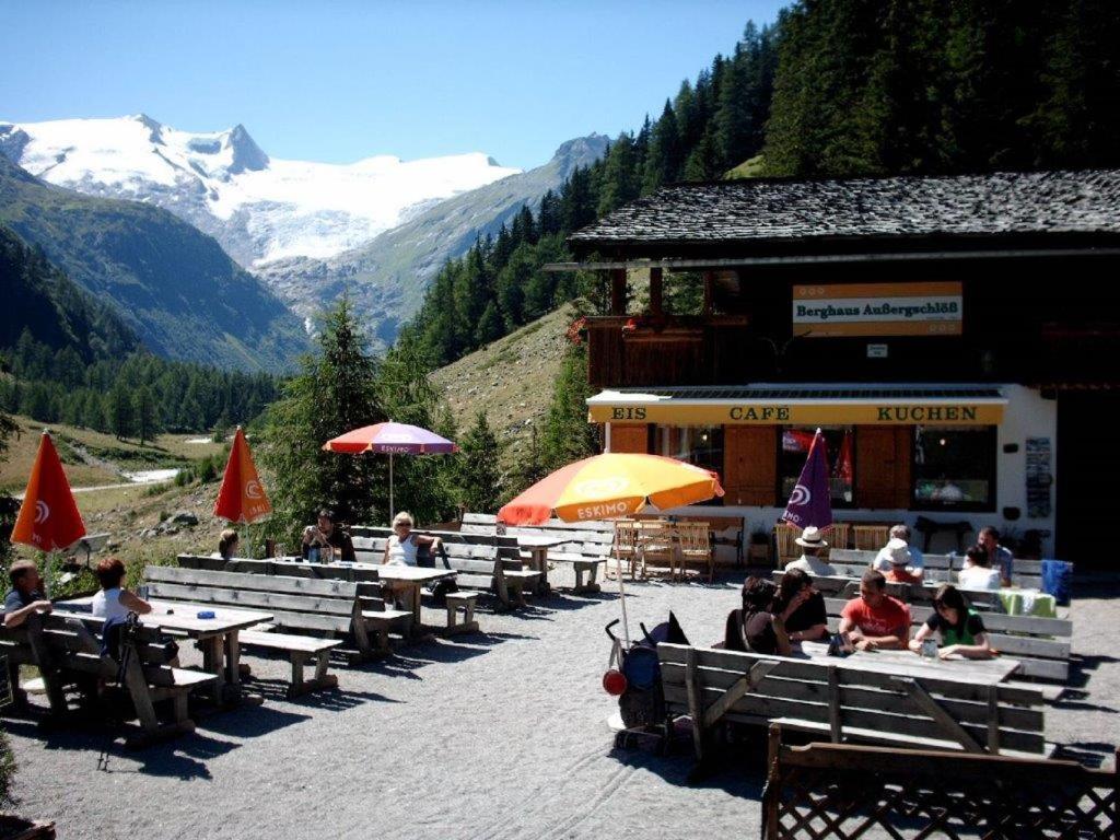 a group of people sitting at tables in front of a building at Berghaus Außergschlöß in Matrei in Osttirol