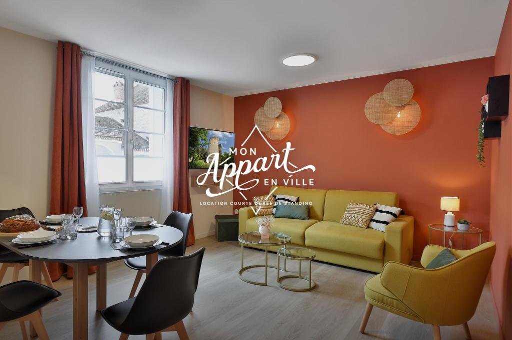a living room with a table and a yellow couch at Le Chic & Raffiné - Terrasse & Climatisé in Périgueux