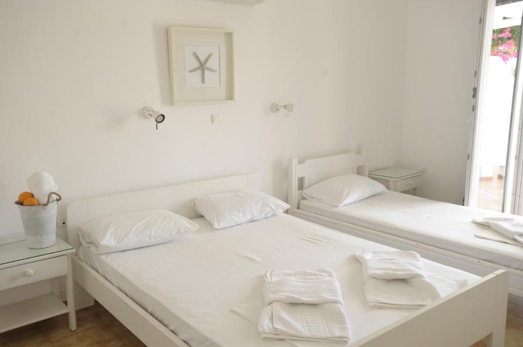 Galatis Beach Hotel في أليكي: غرفة نوم بيضاء بسريرين عليها مناشف