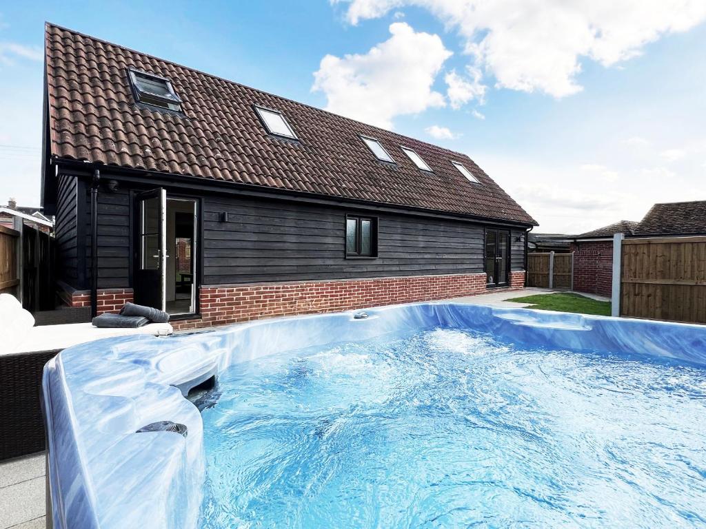 a swimming pool in front of a house at Blackberry Barn by The Suffolk Cottage Collection in Long Melford