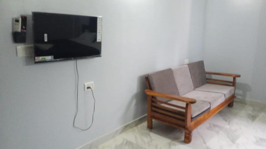 a living room with a chair and a flat screen tv at Calangute Pristine Guest House in Calangute