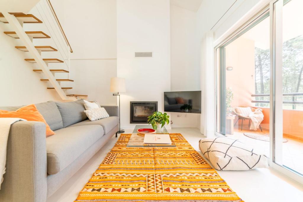 a living room with a couch and a large window at Apartment Aroeira Golf II in Carcereiro