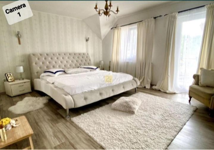 una camera con un grande letto bianco e un tappeto di Vila Eric LG a Budeşti