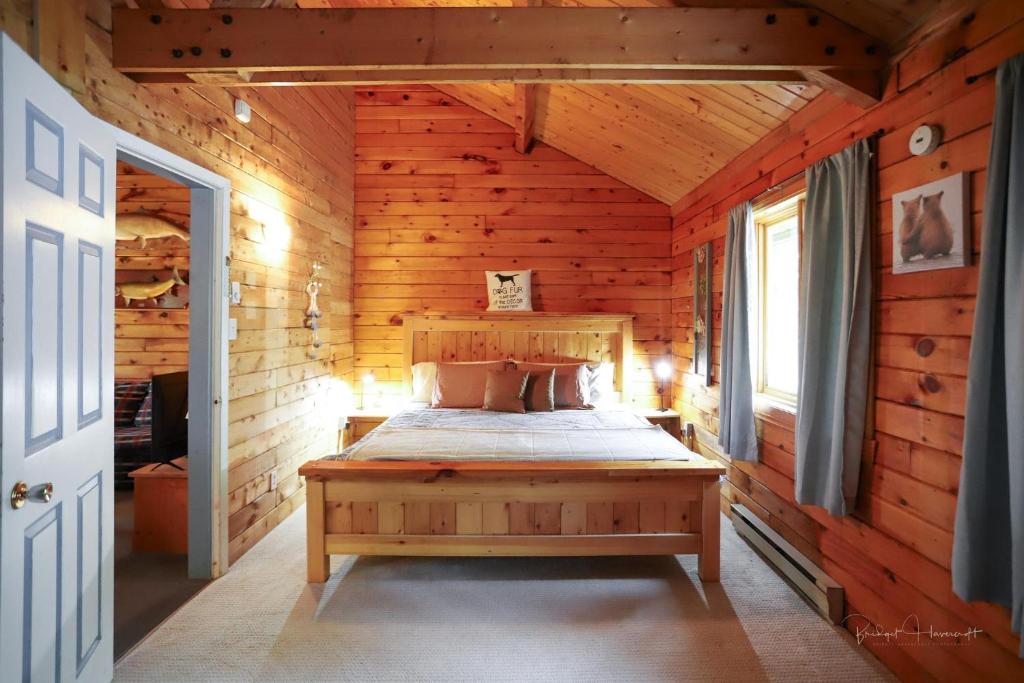 a bedroom with a bed in a wooden cabin at Sherbrooke Lake Cottage with Private Beach in Mahone Bay