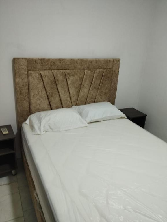 - un lit avec des draps blancs et 2 oreillers dans l'établissement Hotel Quinta Avenida S M, à Santa Marta