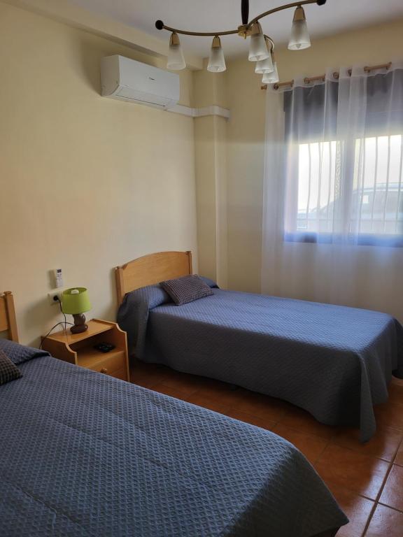 Un dormitorio con dos camas y una ventana. en Pensión Dani, en Casinos