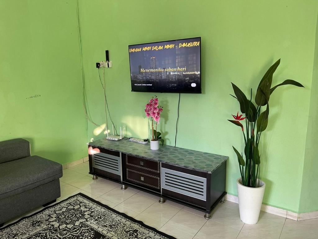 a living room with a tv on a green wall at Tmn Delima Full AC Free WFi&COWAY in Paka