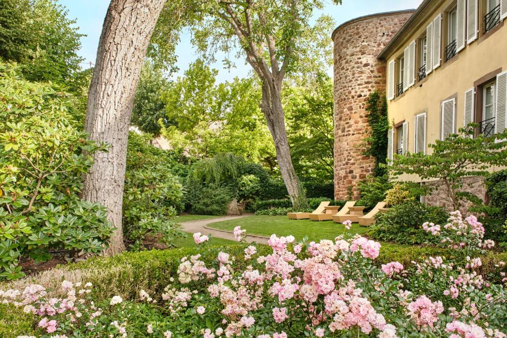 un jardin avec des roses et un banc devant un immeuble dans l'établissement Hotel & Spa A la cour d'Alsace by HappyCulture, à Obernai