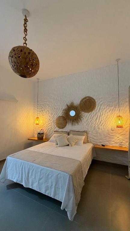 a bedroom with a large white bed and two lights at O Caminho das Dunas in Jericoacoara
