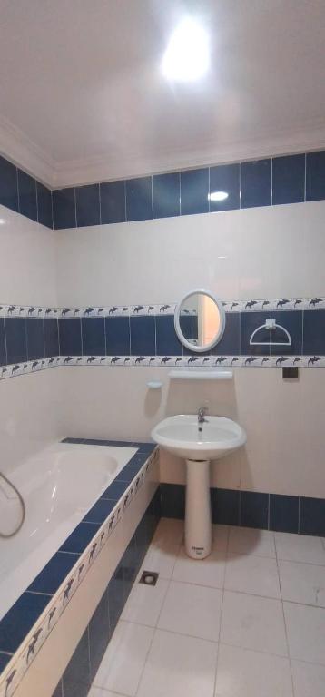a bathroom with a tub and a sink and a mirror at Sidi mahrsi Nabeul in Nabeul