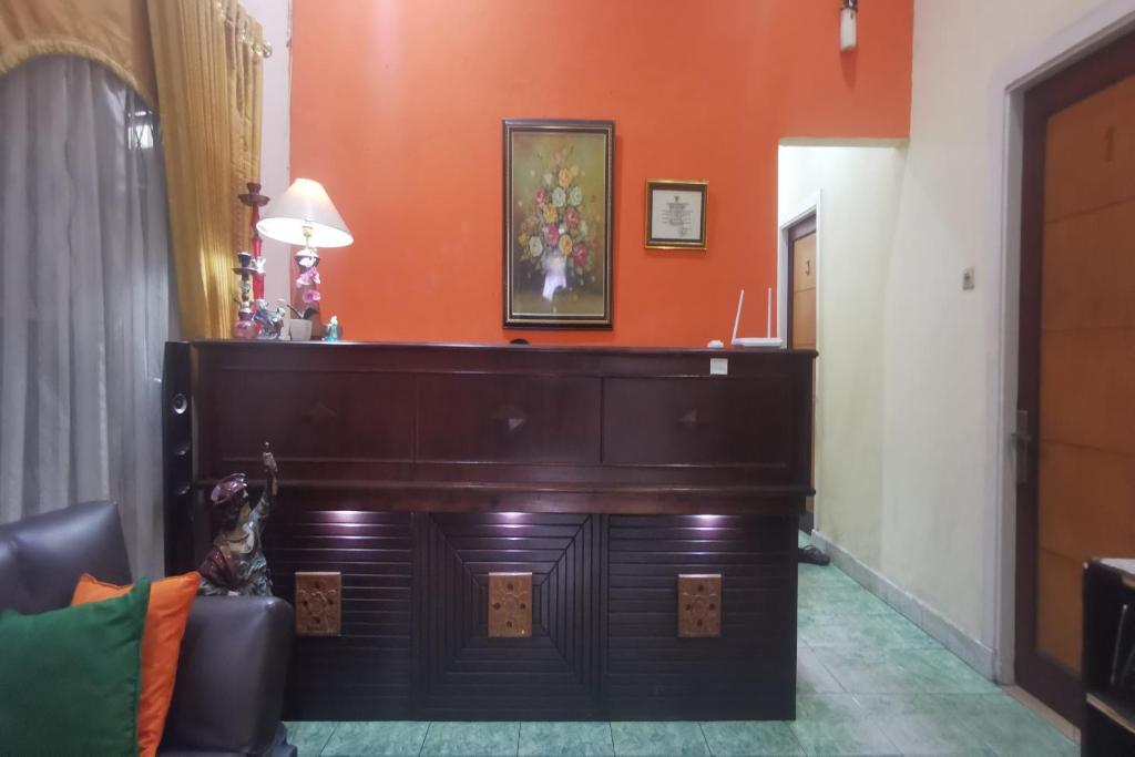 a large piano in a room with an orange wall at Hotel O Classic Guesthouse in Balikpapan