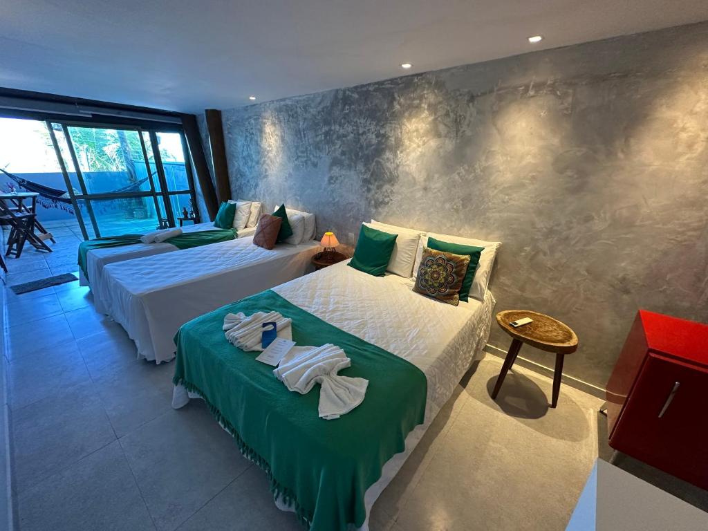 a bedroom with two beds with green and white sheets at Pousada Makai in Porto De Galinhas