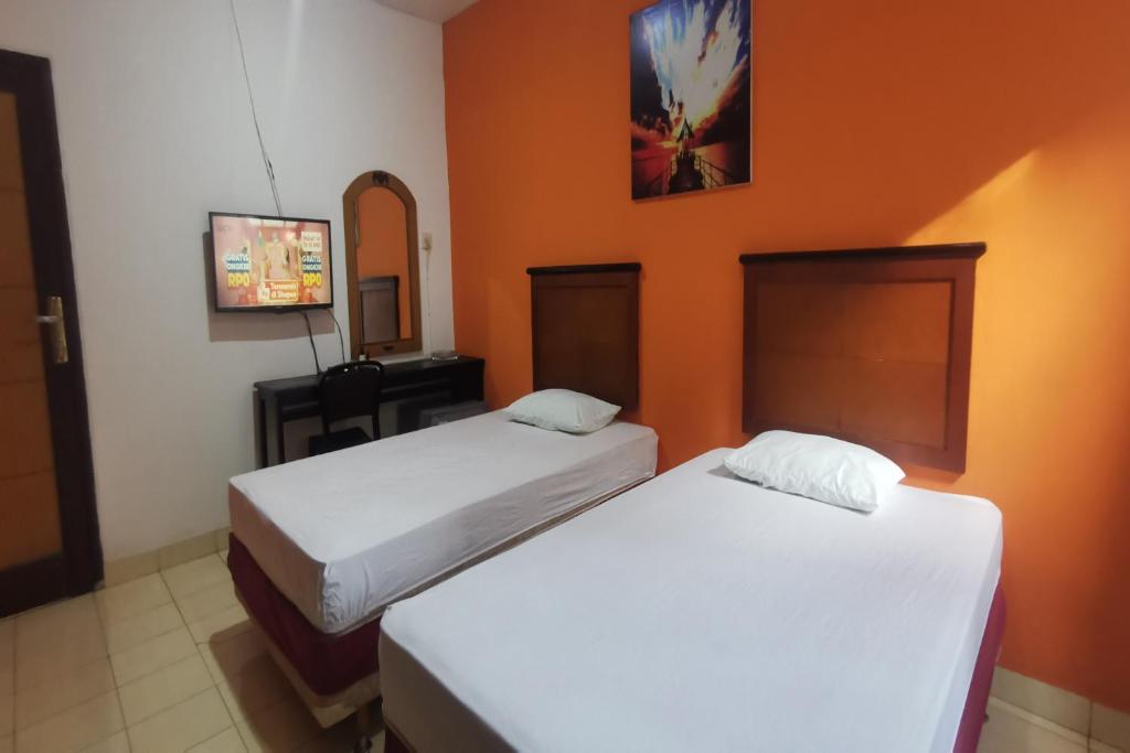 Dos camas en una habitación con paredes naranjas. en Hotel O Classic Guesthouse, en Balikpapan