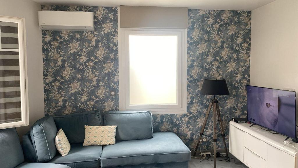 un salon avec un canapé bleu et une fenêtre dans l'établissement Pavillon 50 m² avec terrasse, à Châtelaillon-Plage