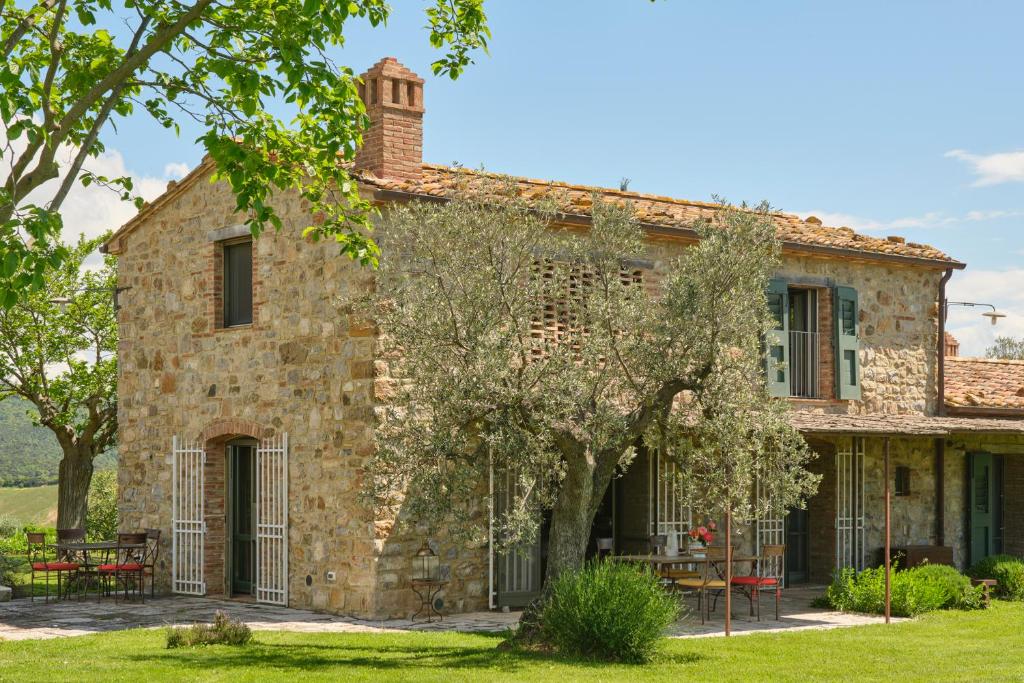 una vecchia casa in pietra con un albero di fronte di Sequerciani a Tatti