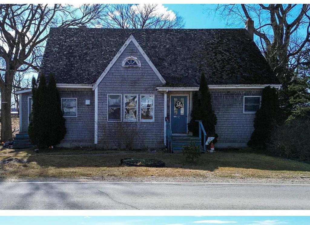 a small house with a blue door on a street at Sawyer Cove Cottage in Jonesport