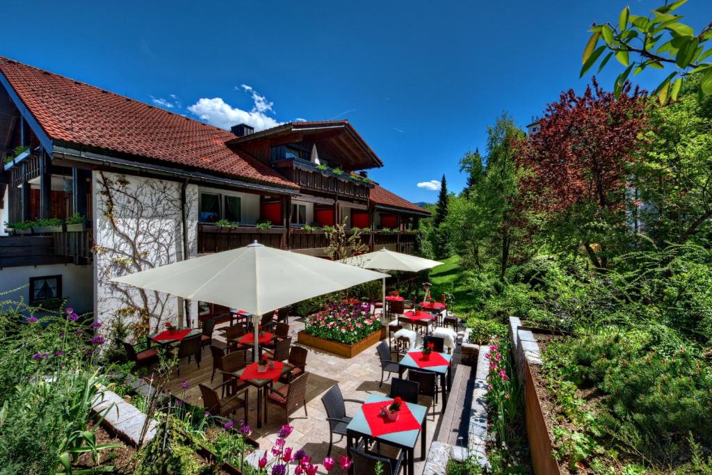 an outdoor patio with tables and umbrellas at DIANA Naturpark Hotel - mit Oberstaufen Plus Golf in Oberstaufen