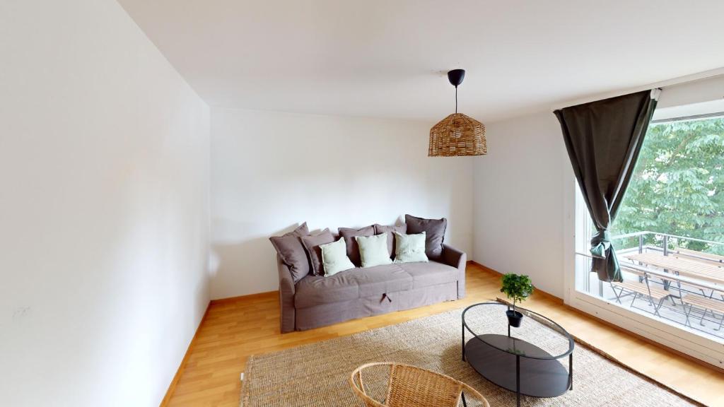 a living room with a couch and a large window at Basic Comforts for Your Stay in Zürich