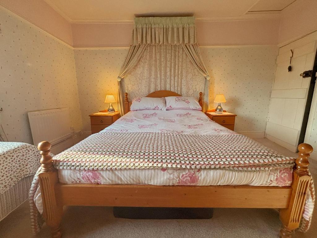 ein Schlafzimmer mit einem Bett mit zwei Lampen auf zwei Tischen in der Unterkunft Charming Lilac Cottage, Aldbrough, East Yorkshire in Aldbrough