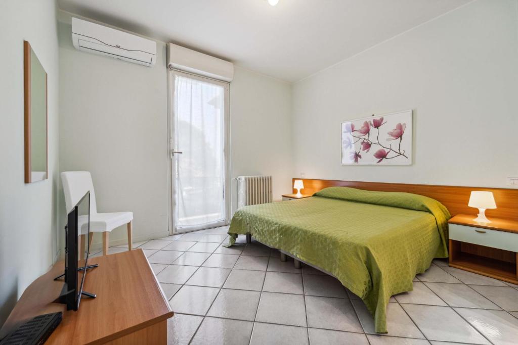 a bedroom with a bed and a television in it at Green Village Accommodations in Colico