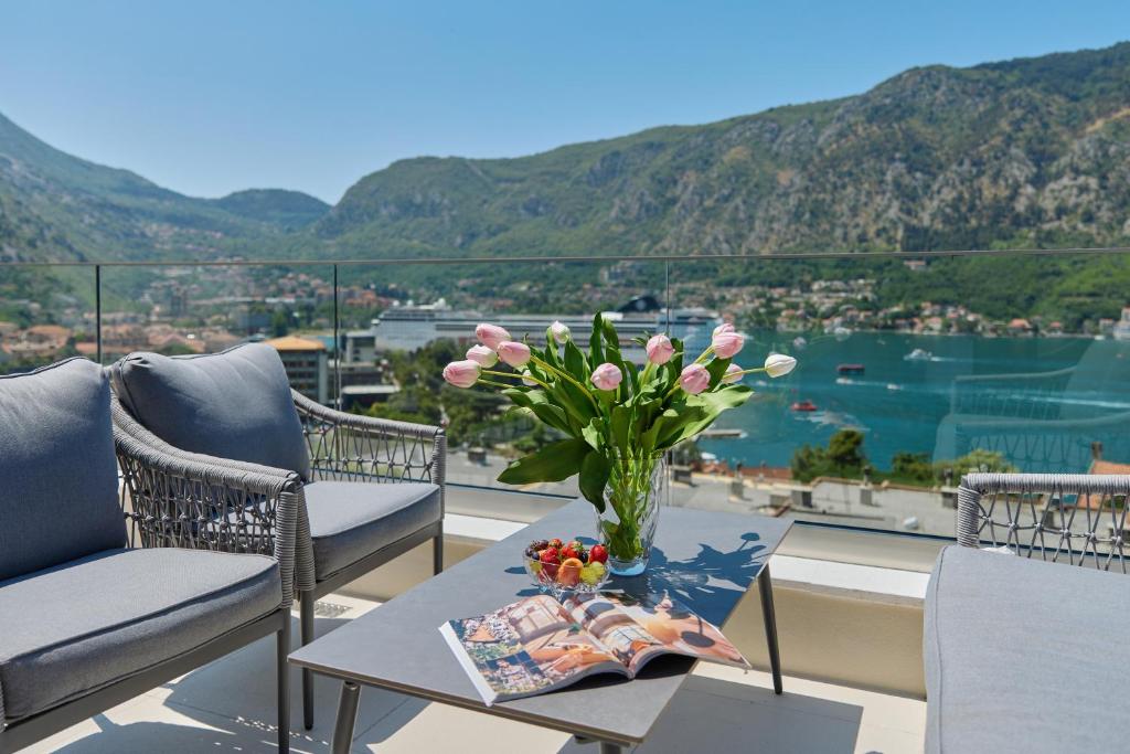 a vase with pink flowers on a table on a balcony at Berge Apartments in Kotor