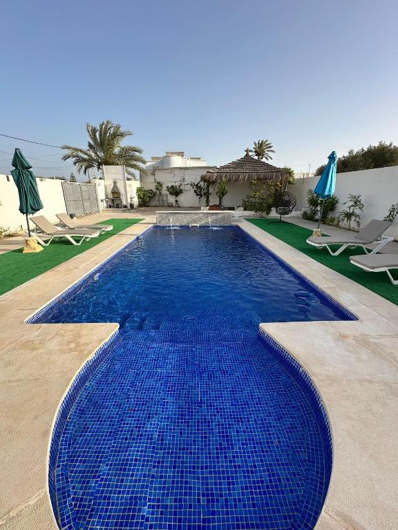 a large blue swimming pool in a resort at Villa Line Midoun sans vis-à-vis in Taguermess