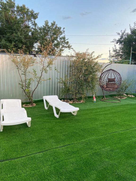 a yard with two white benches and a swing at Волна in Balqash