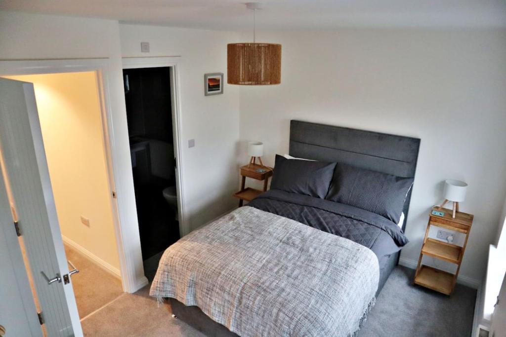 a bedroom with a bed with a gray comforter at Lower Townhouse, Exeter in Alphington