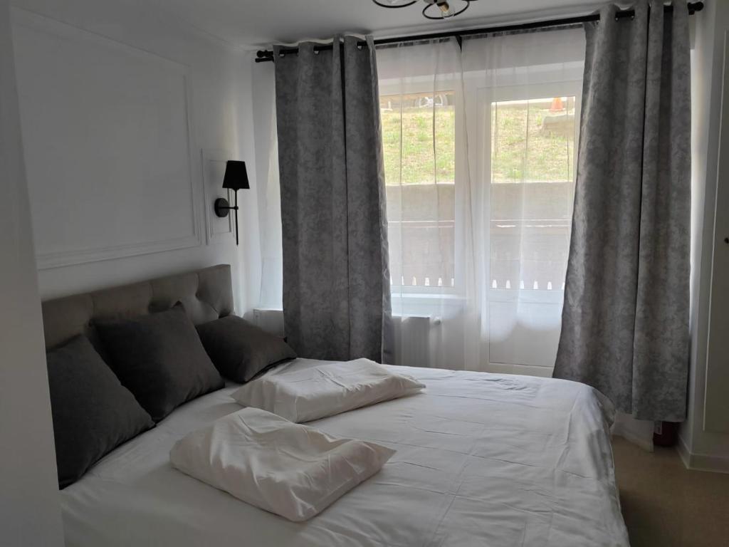 a bed with two pillows in front of a window at Studio Poiana Brasov in Poiana Brasov