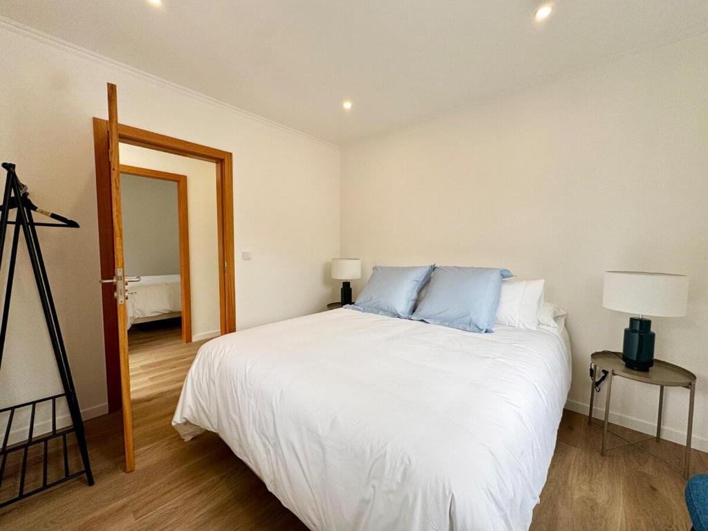 a bedroom with a large white bed with blue pillows at Cottage - A Casa da Avó in São Vicente