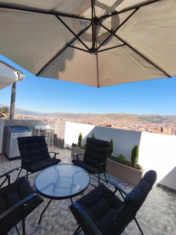 eine Terrasse mit Stühlen, einem Tisch und einem Sonnenschirm in der Unterkunft La Casita De Colores Cusco in Cusco