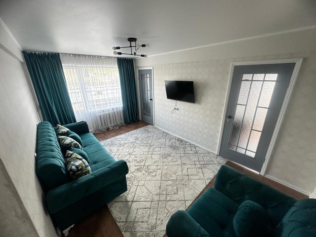 een woonkamer met groene banken en een televisie bij LuxHome на УК in Öskemen
