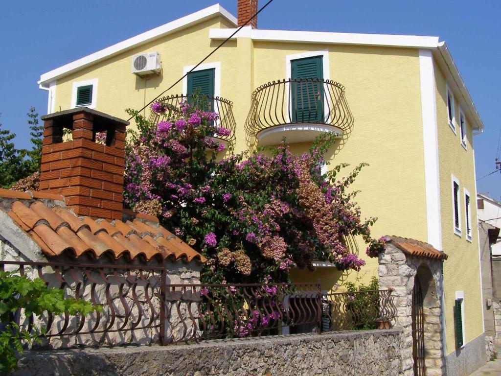 a yellow house with flowers on a fence at Apartment Kukljica 7 in Kukljica