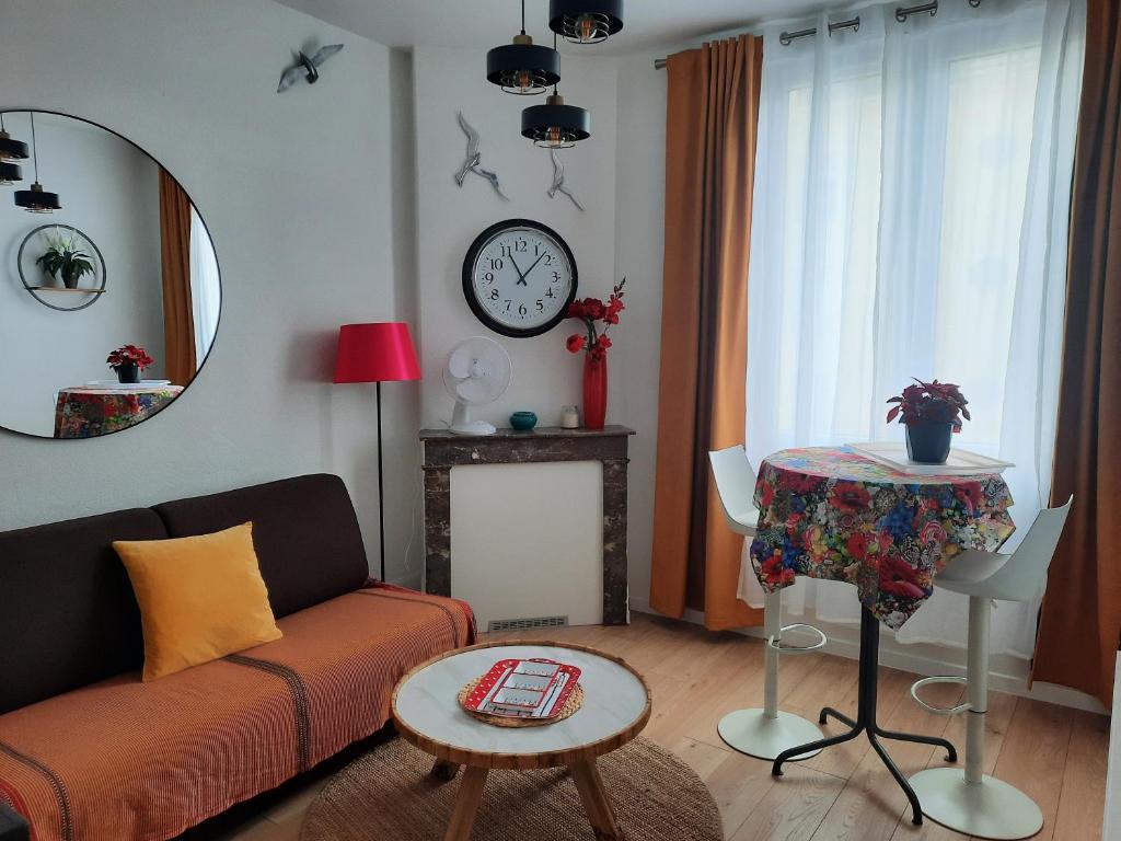a living room with a couch and a table and a clock at LA GRANV'ILLAISE in Granville