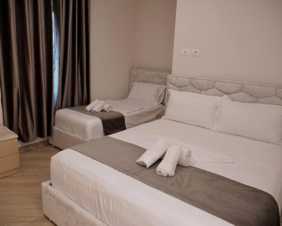 two beds in a room with white towels on them at Cozy Room for Three in Kamëz
