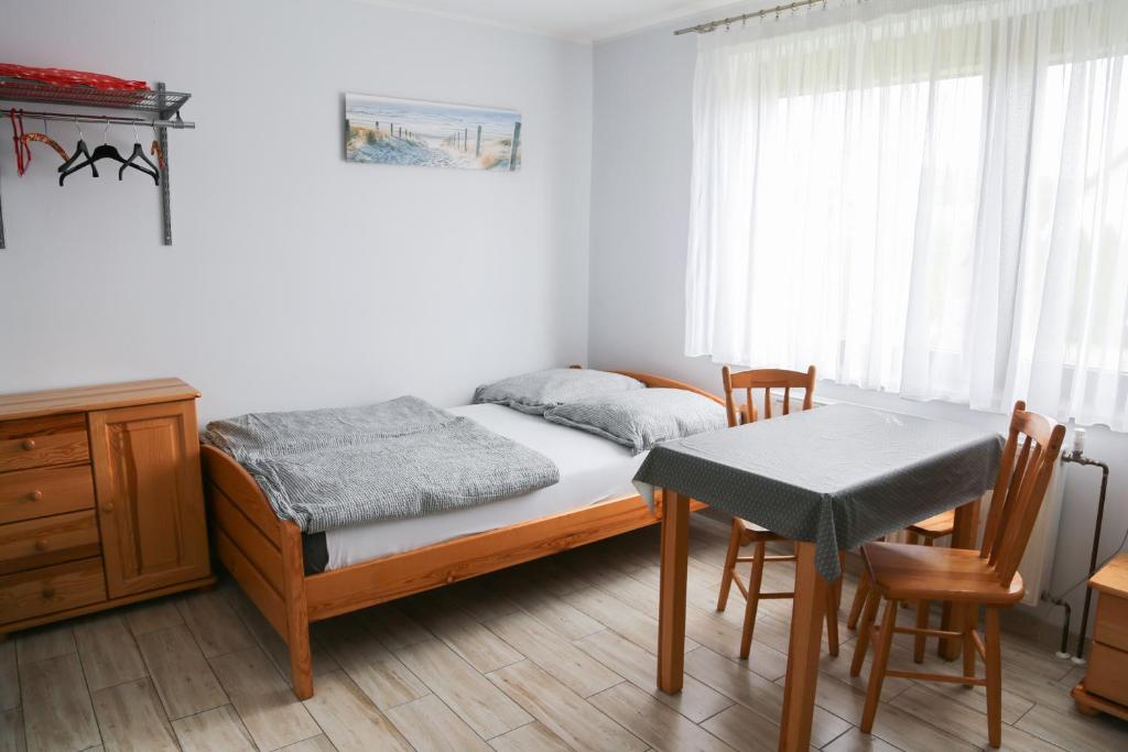 Un pequeño dormitorio con una cama y una mesa. en Pokoje u SŁONIA, en Stegna