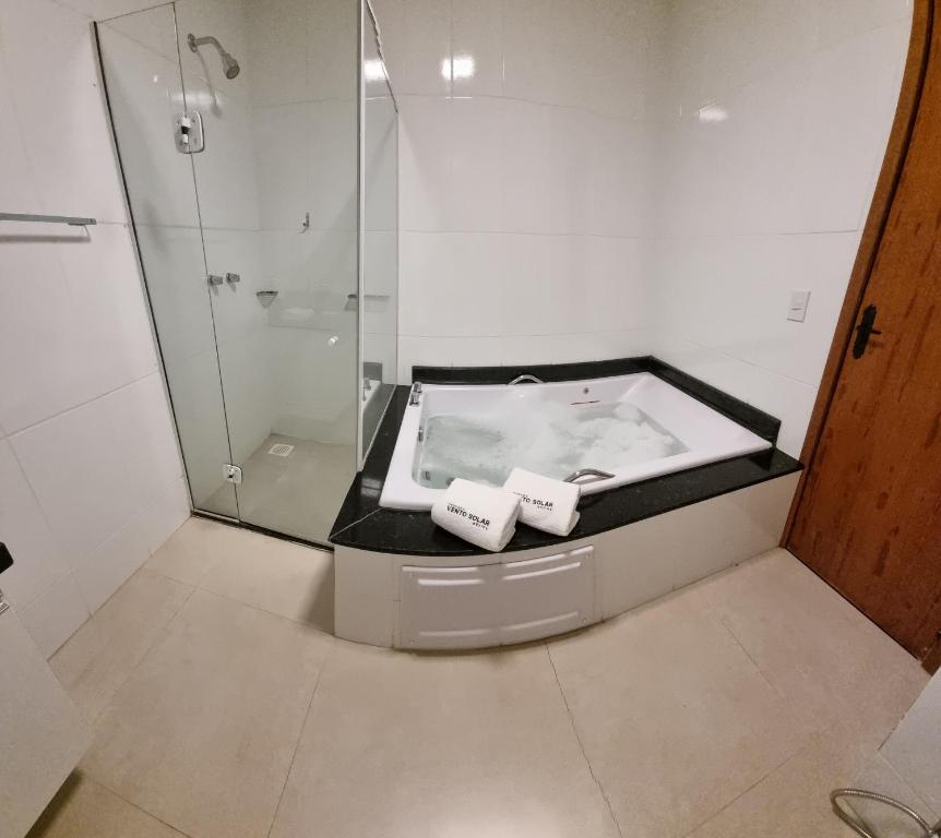 a bathroom with a bath tub and a shower at Suites Vento Solar Buzios in Búzios