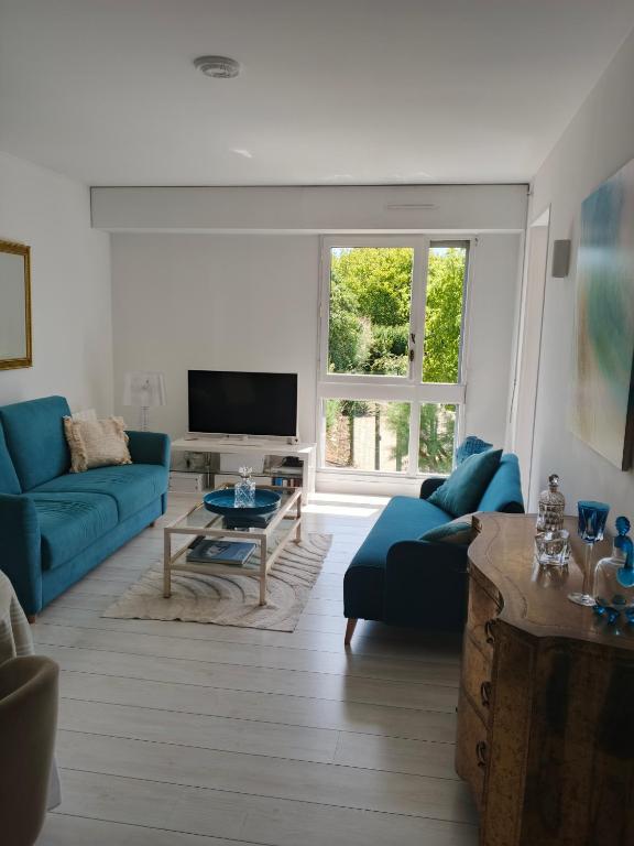 a living room with blue couches and a tv at T2 loggia et piscine in La Rochelle