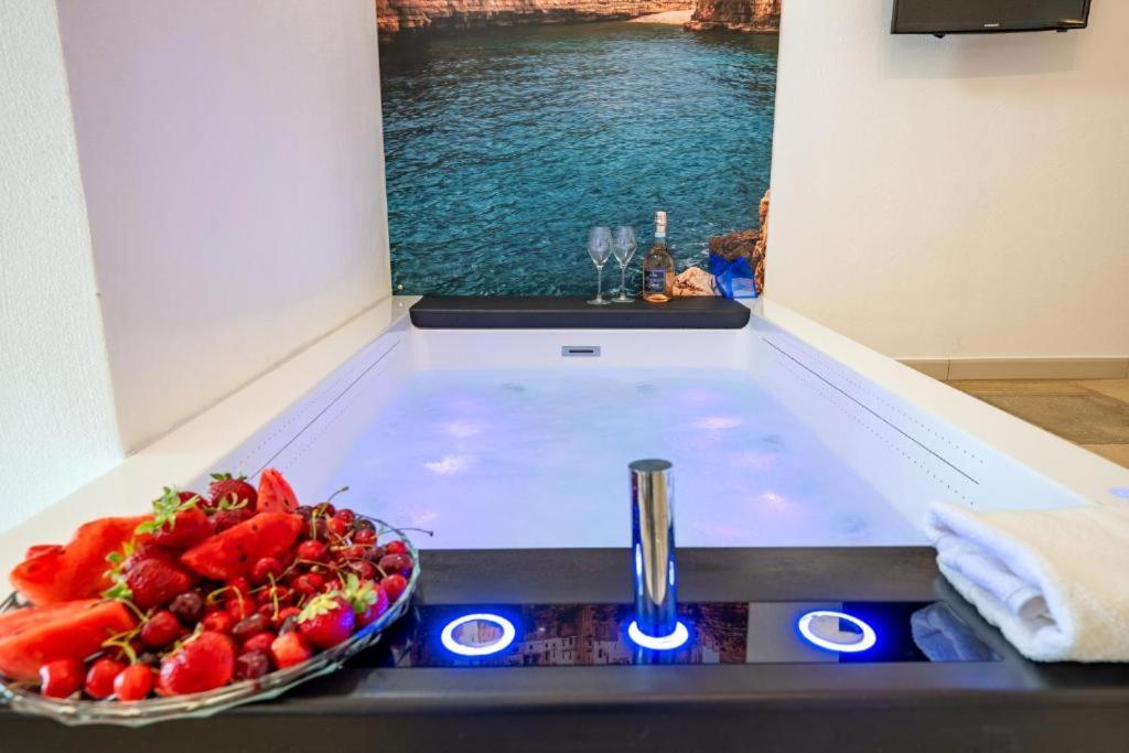 Un tazón de fresas en una encimera de cocina con fregadero. en Le Perle di Bà - Suites with Jacuzzi in Polignano, en Polignano a Mare