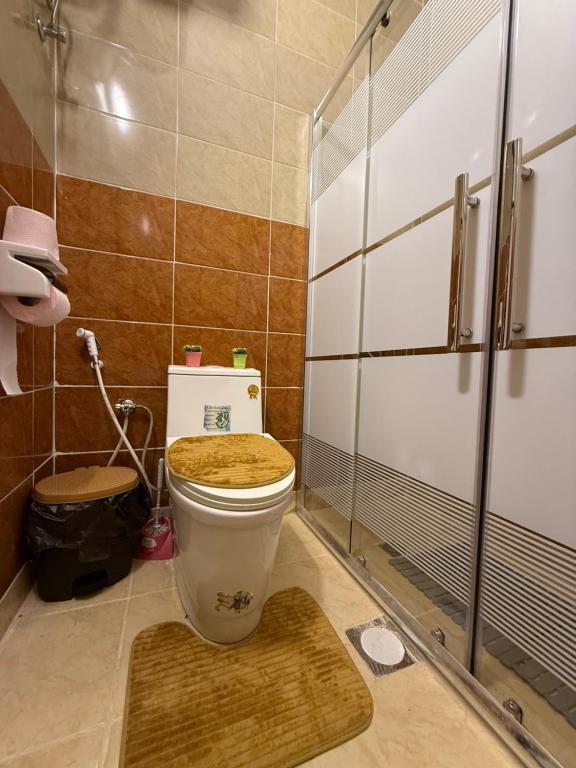 een badkamer met een toilet en een houten stoel bij Beit Ahlam Quiet Duplex Villa with Terrace and Scenic View near Umm Qais Ruins in Um Qeis